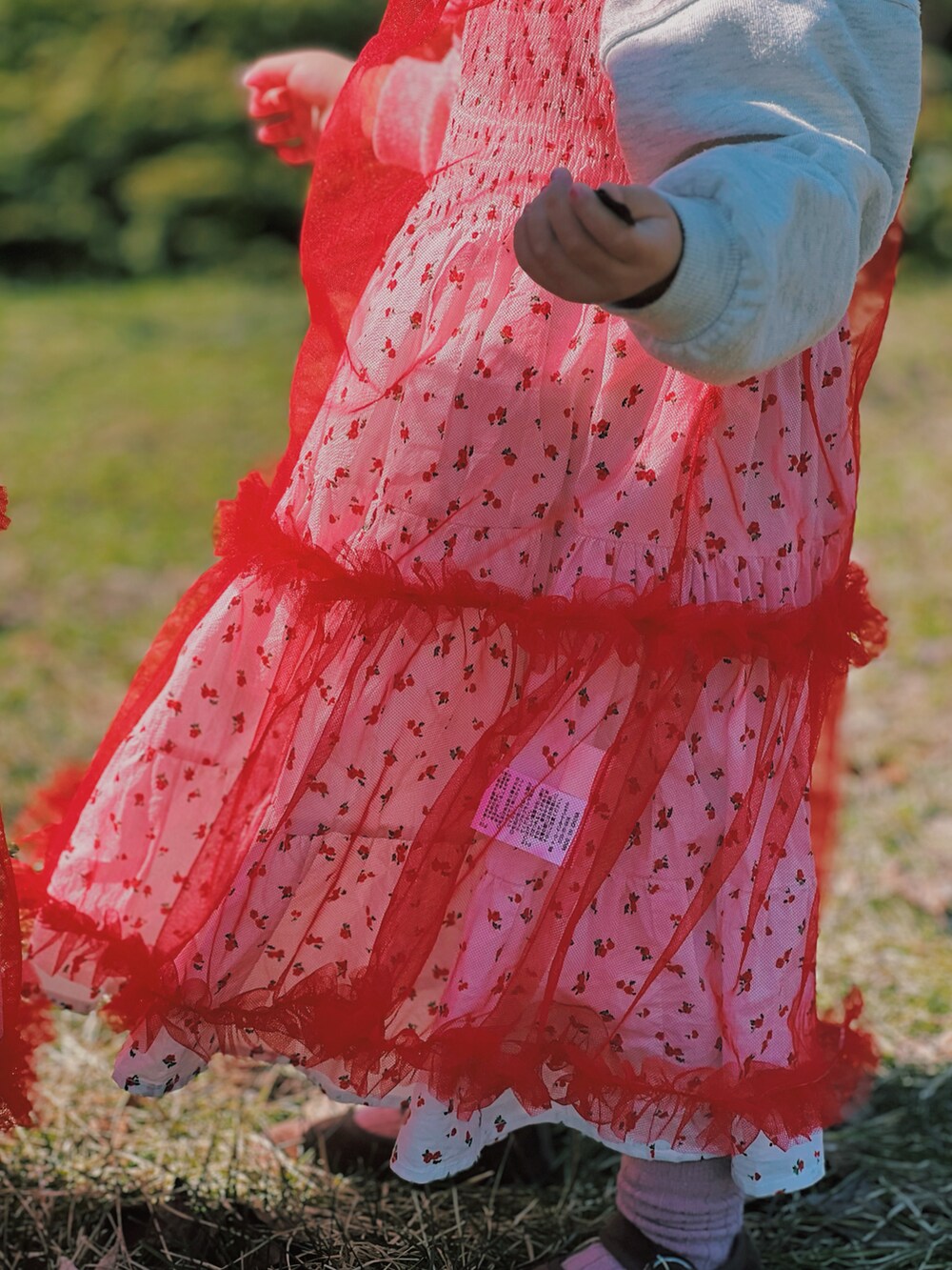 レッド系のワンピースを着用したキッズの春コーディネートの3枚目の写真