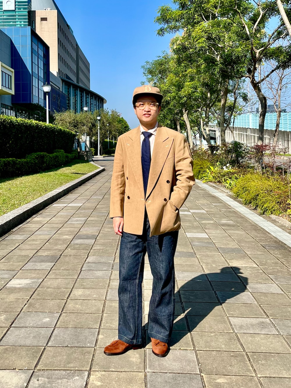 ブルー系のデニムパンツ、ベージュ系のチェスターコート、ブラウン系のローファーを着用したメンズの春コーディネートの2枚目の写真