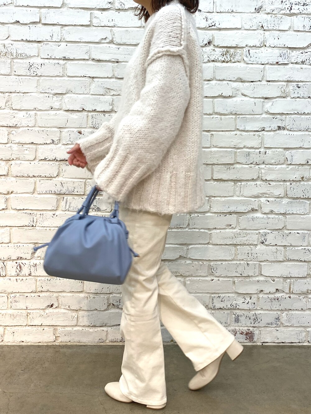 ホワイト系のデニムパンツ、ホワイト系のブーツ、ホワイト系のニット/セーターを着用したレディースの秋コーディネートの3枚目の写真