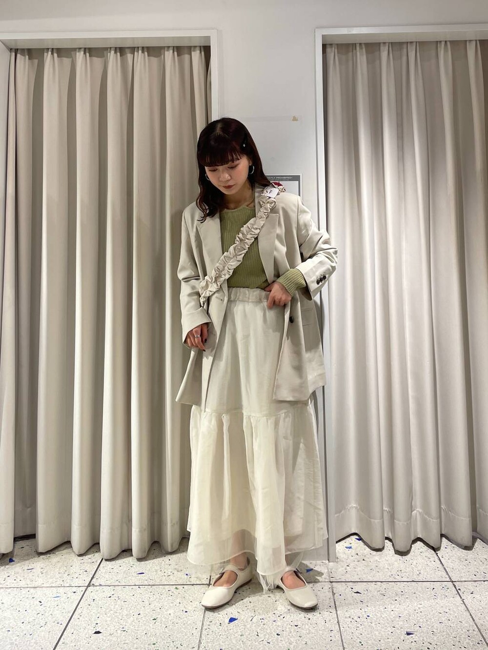 グリーン系のニット/セーター、ホワイト系のパンプス、ホワイト系のテーラードジャケットを着用したレディースの冬コーディネートの3枚目の写真