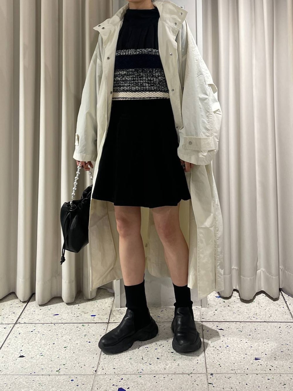 ブラック系のニット/セーター、ブラック系のブーツ、ホワイト系のブルゾンを着用したレディースの春コーディネートの2枚目の写真