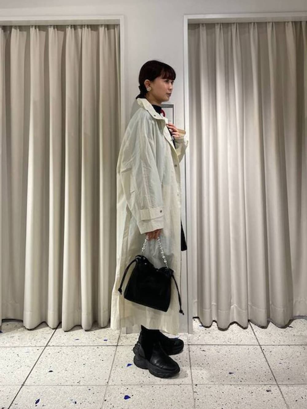 ブラック系のニット/セーター、ブラック系のブーツ、ホワイト系のブルゾンを着用したレディースの春コーディネートの3枚目の写真