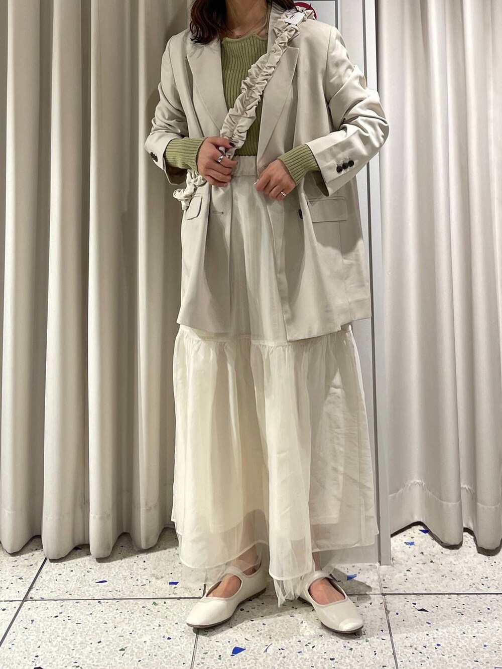 グリーン系のニット/セーター、ホワイト系のパンプス、ホワイト系のテーラードジャケットを着用したレディースの冬コーディネートの2枚目の写真