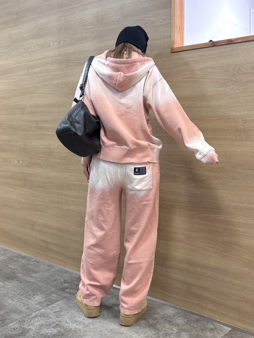 ピンク系のパーカー、ピンク系のスウェットパンツ、ブラック系のショルダーバッグを着用したレディースの冬コーディネートの3枚目の写真