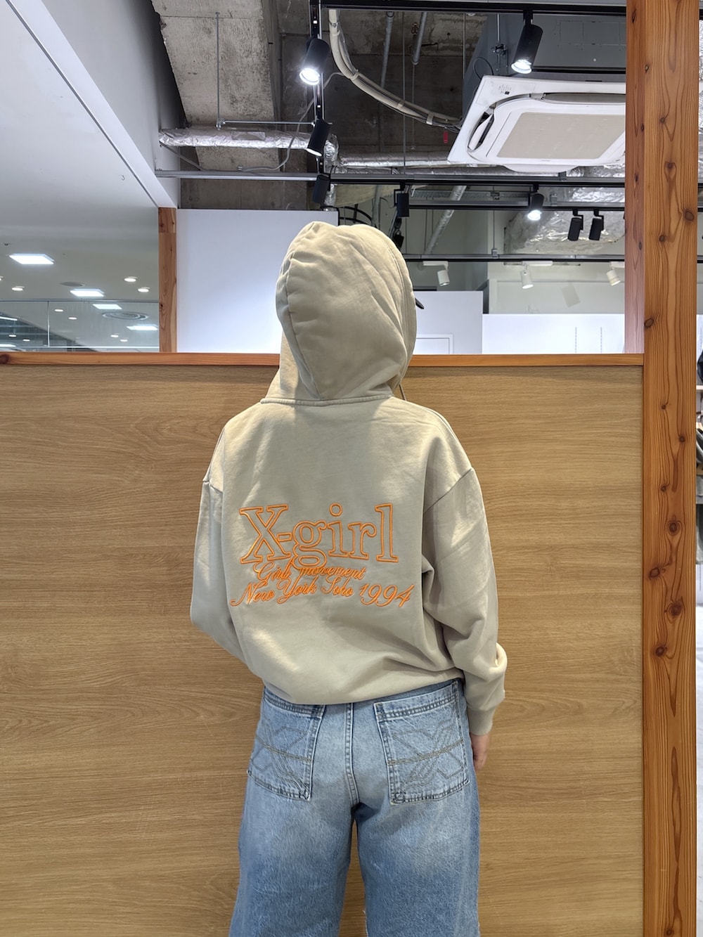 ベージュ系のパーカー、ブルー系のデニムパンツ、ブラック系のキャップを着用したレディースの春コーディネートの4枚目の写真