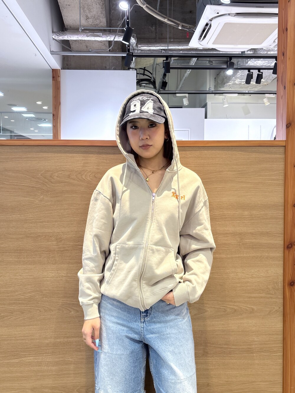 ベージュ系のパーカー、ブルー系のデニムパンツ、ブラック系のキャップを着用したレディースの春コーディネートの5枚目の写真