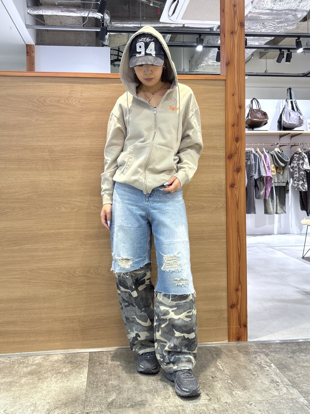 ベージュ系のパーカー、ブルー系のデニムパンツ、ブラック系のキャップを着用したレディースの春コーディネートの2枚目の写真