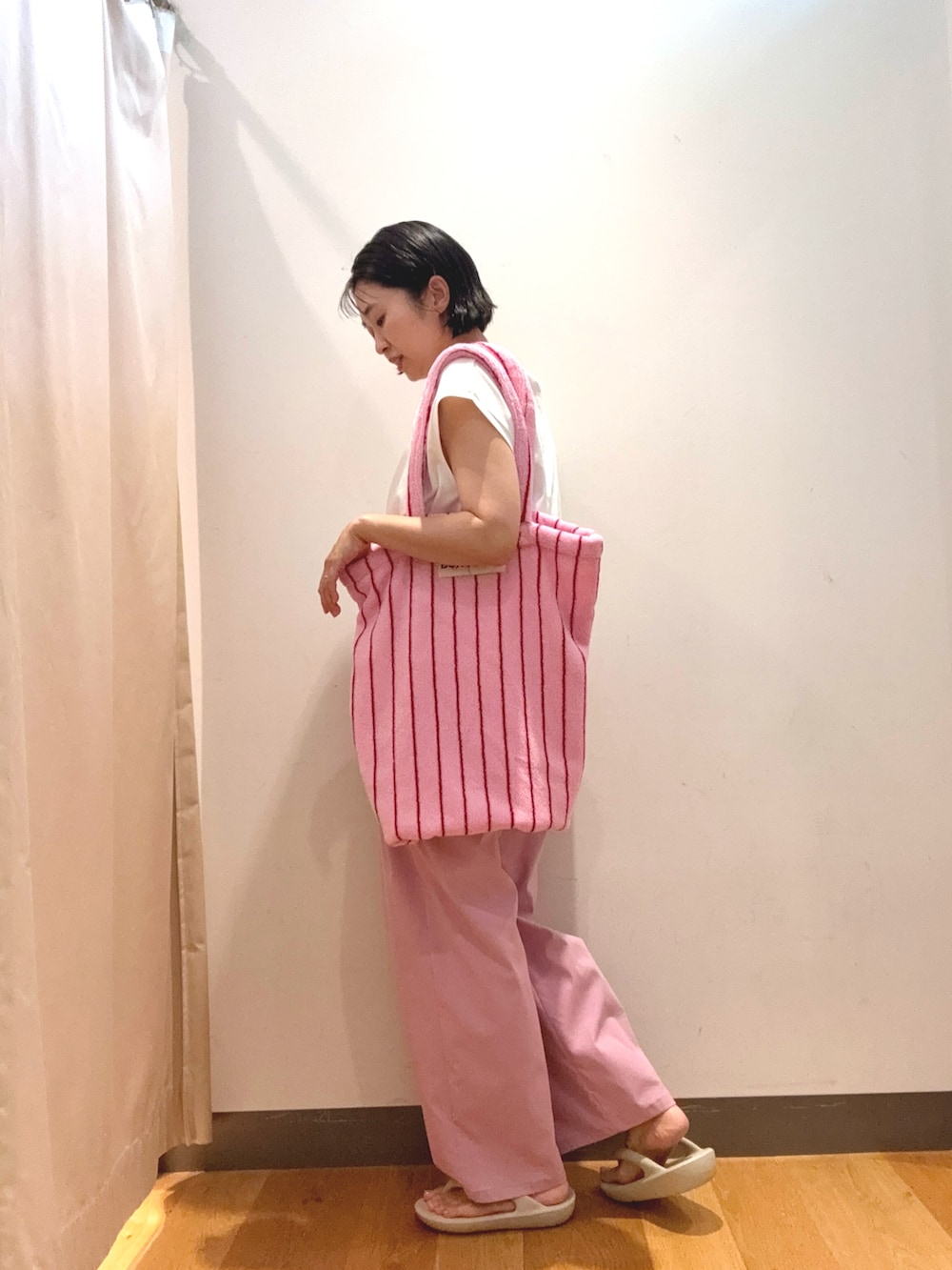 ホワイト系のTシャツ/カットソー、ピンク系のトートバッグ、ホワイト系のサンダルを着用したレディースの夏コーディネートの3枚目の写真
