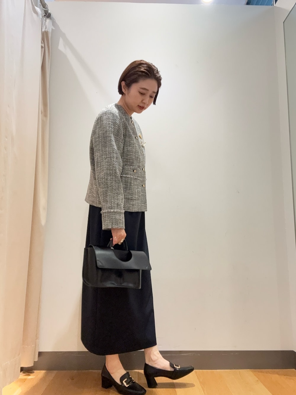 ブラック系のノーカラージャケット、ブルー系のワンピース、ブラック系のパンプスを着用したレディースの冬コーディネートの2枚目の写真