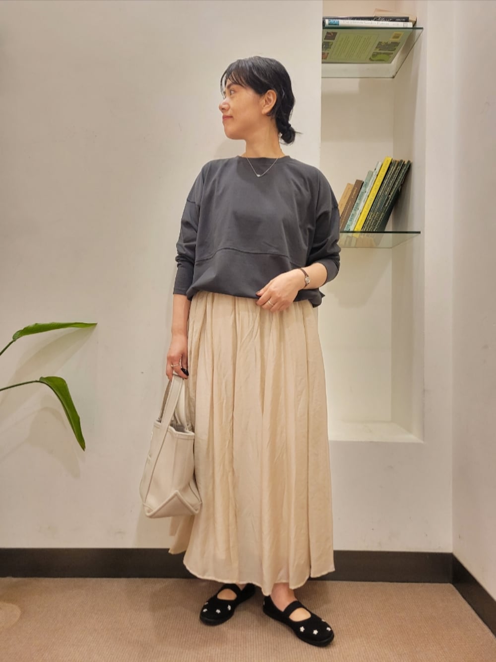 グレー系のTシャツ/カットソー、ベージュ系のスカート、ブラック系のスニーカーを着用したレディースの秋コーディネートの2枚目の写真