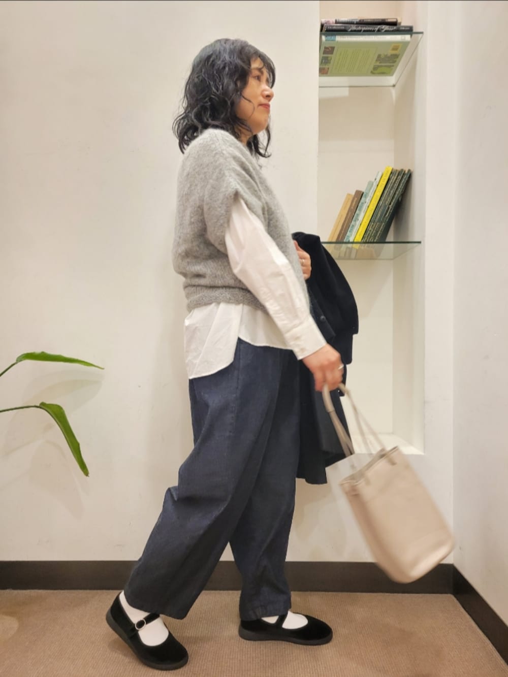 グレー系のショルダーバッグ、ブラック系のその他シューズ、ブルー系のデニムパンツを着用したレディースの秋コーディネートの5枚目の写真