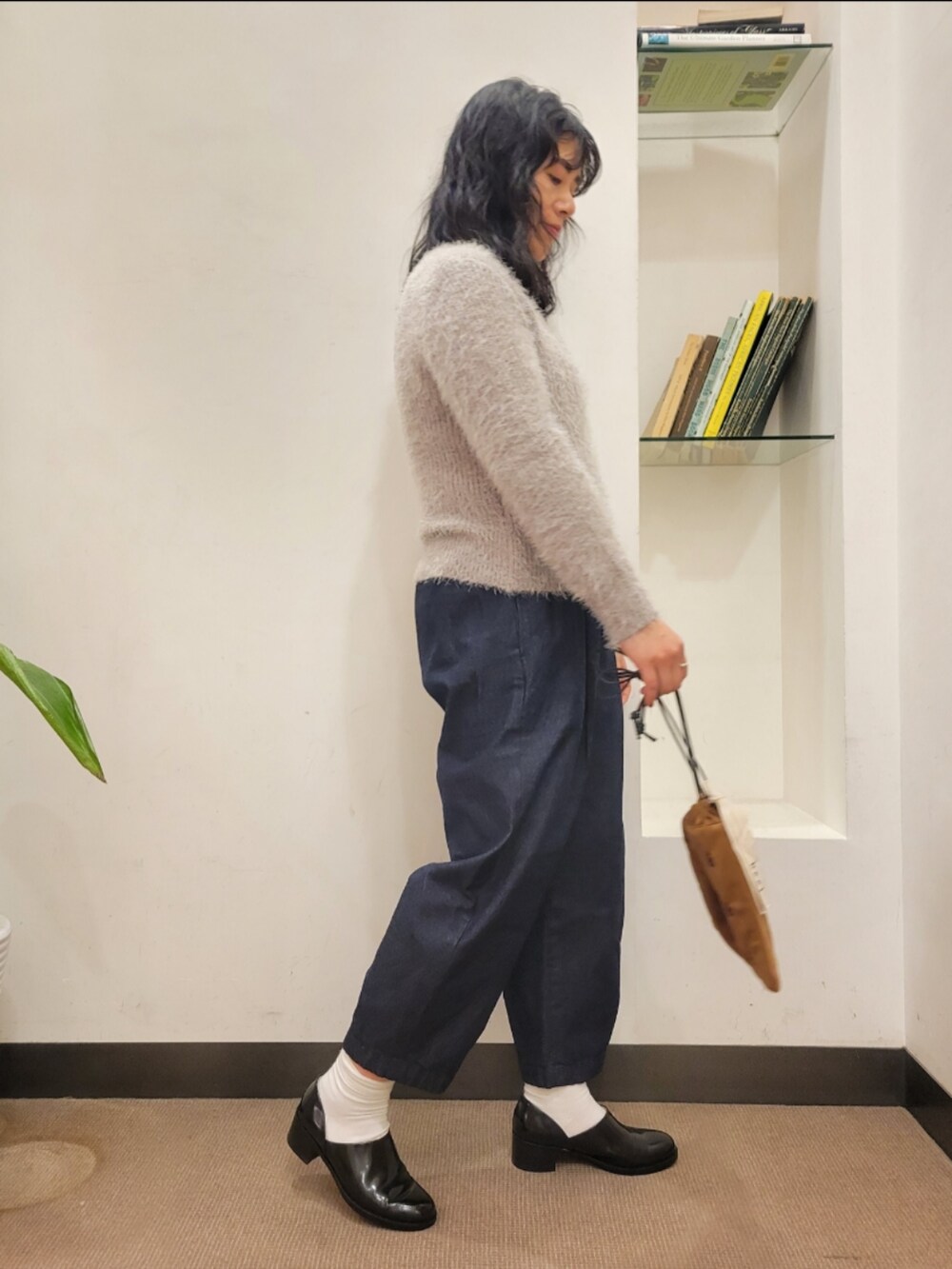 ブラック系のレインシューズ、ブラウン系のショルダーバッグ、グレー系のニット/セーターを着用したレディースの冬コーディネートの3枚目の写真