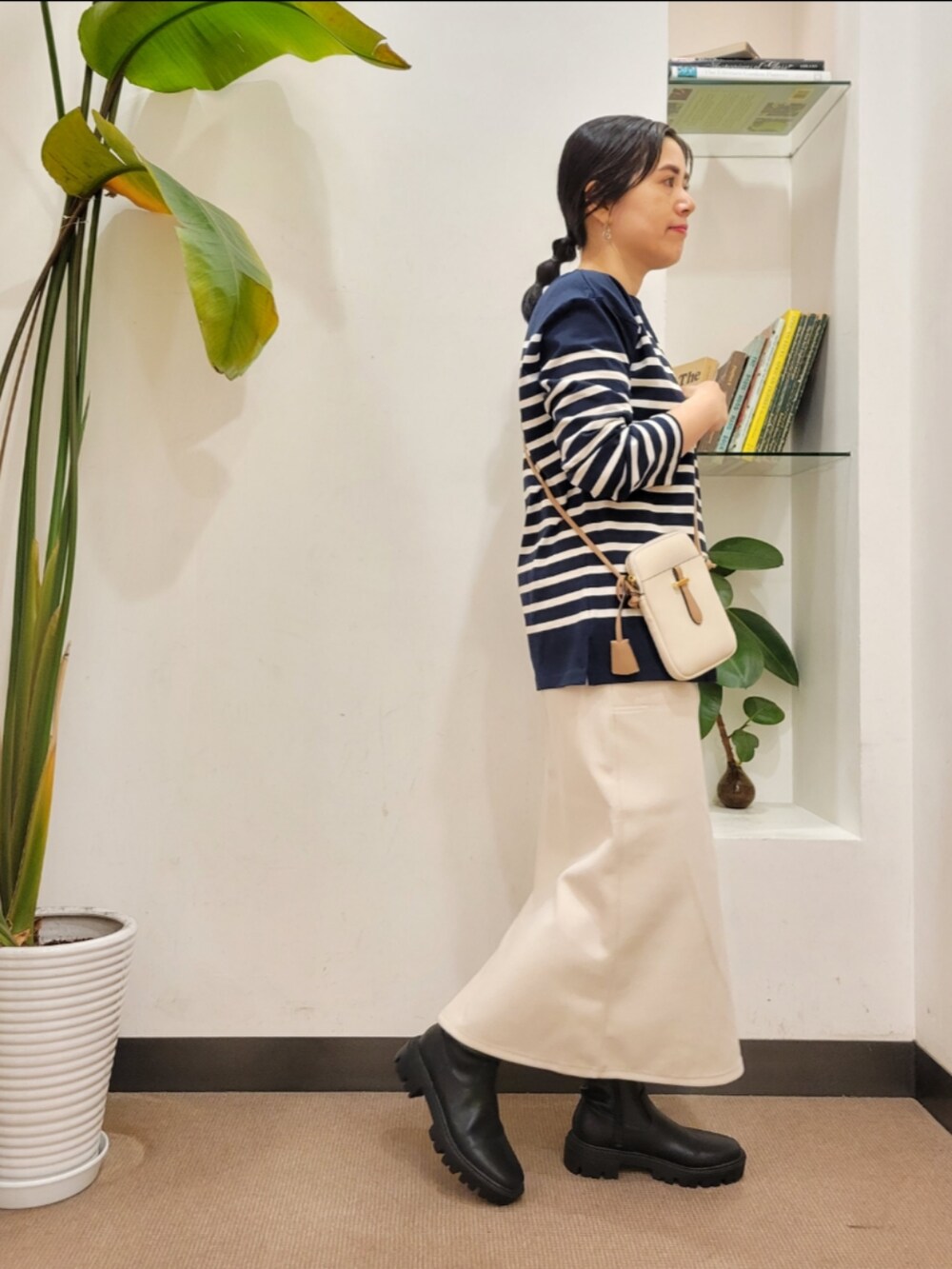 ホワイト系のショルダーバッグ、ブラック系のブーツ、ホワイト系のスカートを着用したレディースの秋コーディネートの3枚目の写真