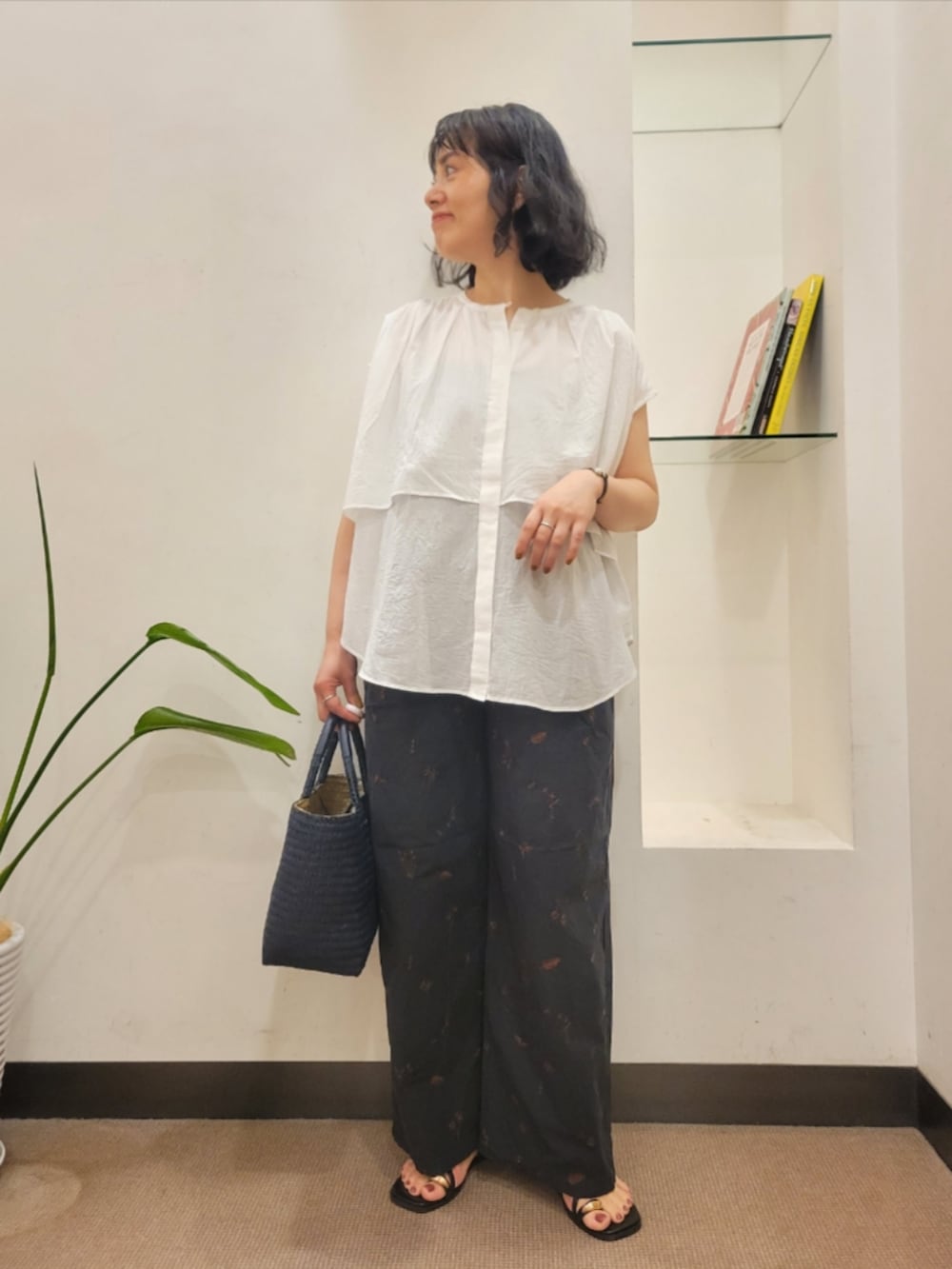 ブルー系のトートバッグ、ホワイト系のシャツ/ブラウス、ブラック系のサンダルを着用したレディースの夏コーディネートの2枚目の写真