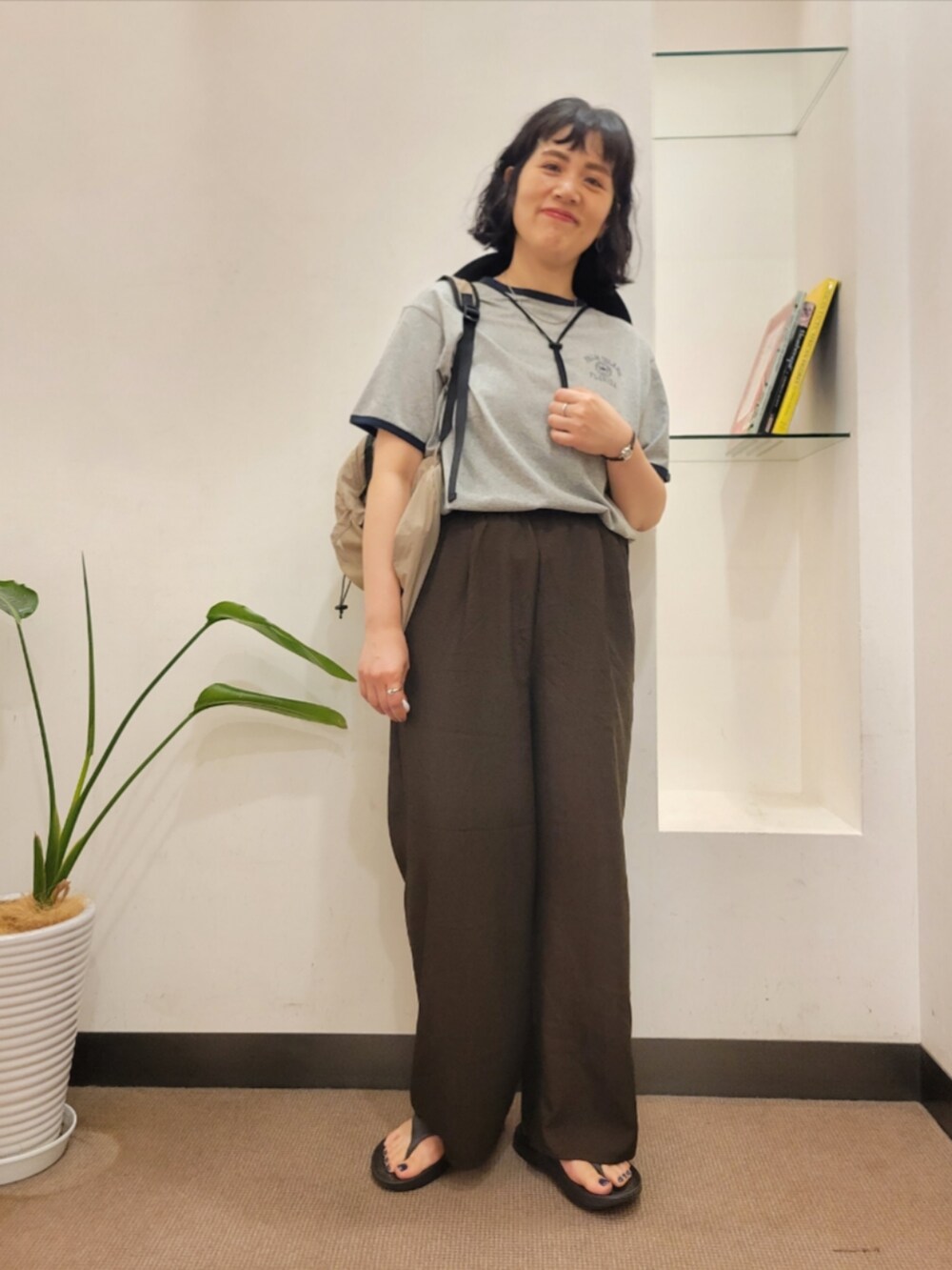 ベージュ系のバックパック/リュック、グレー系のTシャツ/カットソー、ブラウン系のその他パンツを着用したレディースの夏コーディネートの2枚目の写真