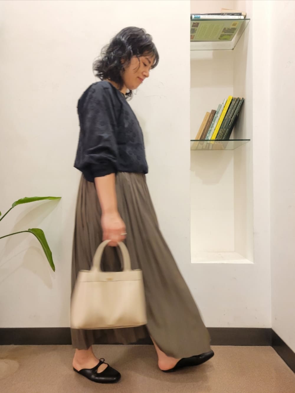 ベージュ系のスカート、ブラック系のシャツ/ブラウス、ブラック系のサンダルを着用したレディースの秋コーディネートの3枚目の写真