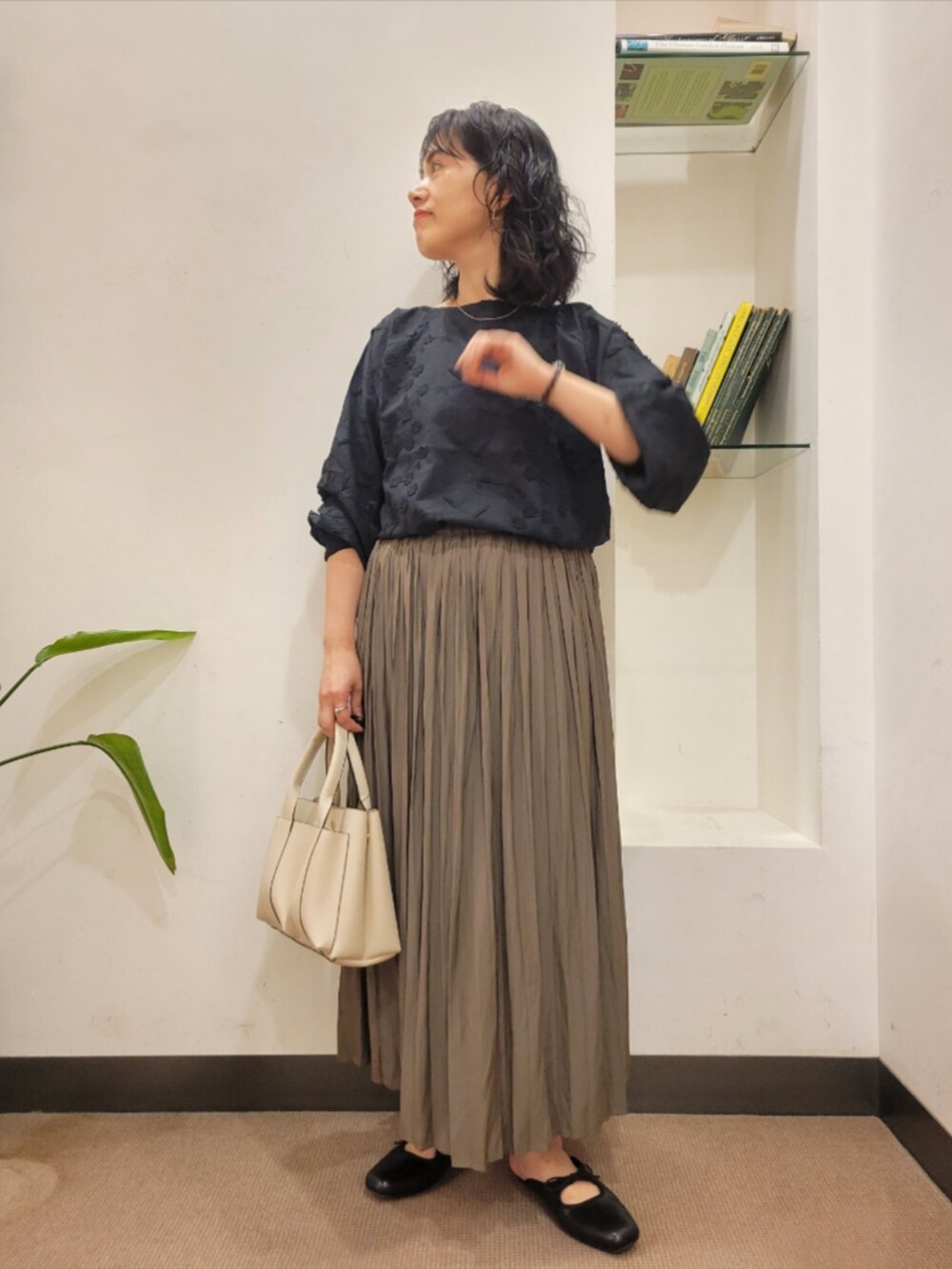 ベージュ系のスカート、ブラック系のシャツ/ブラウス、ブラック系のサンダルを着用したレディースの秋コーディネートの2枚目の写真