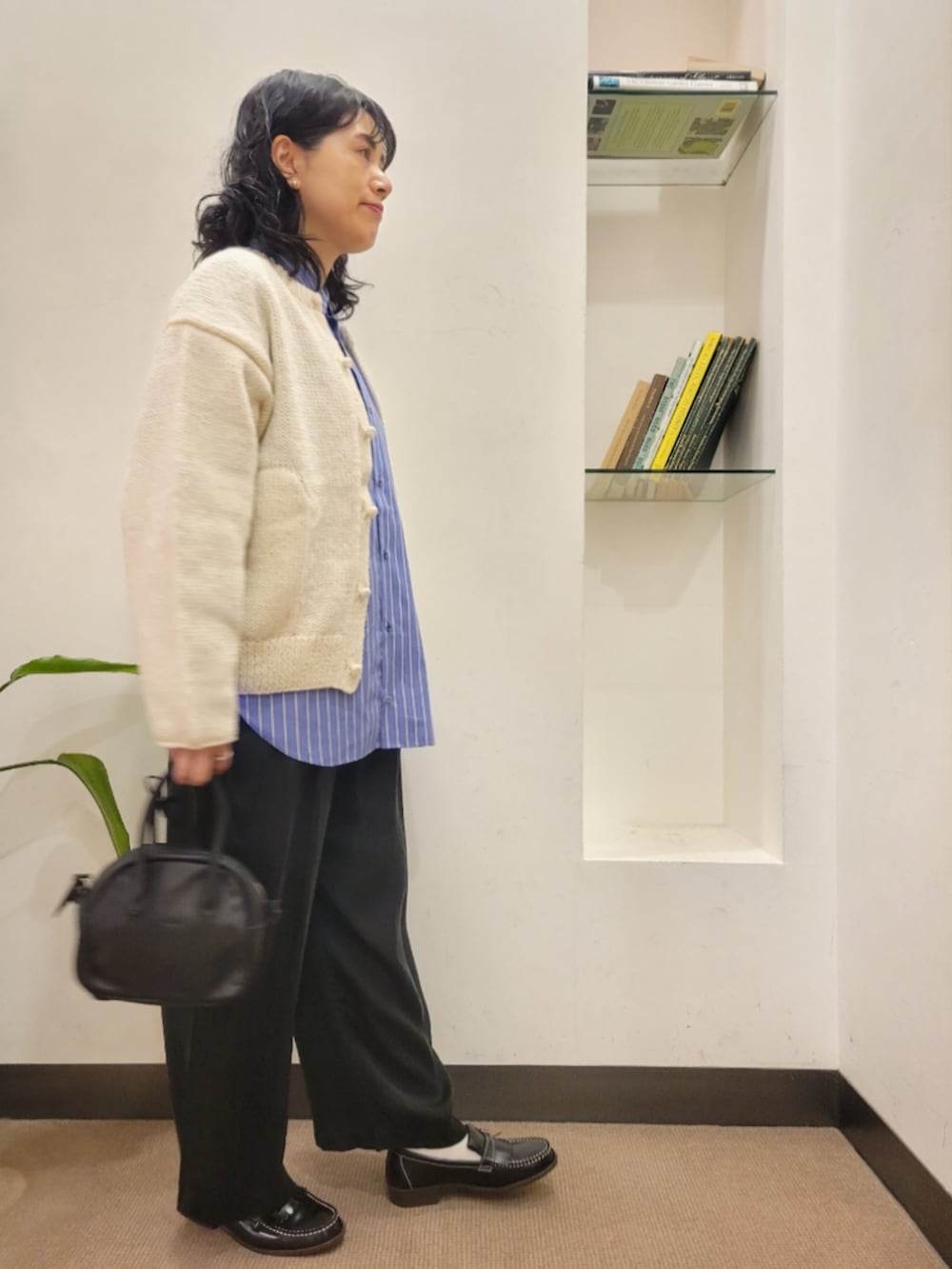 ブラック系のハンドバッグ、ブラック系のローファー、ホワイト系のニット/セーターを着用したレディースの秋コーディネートの2枚目の写真