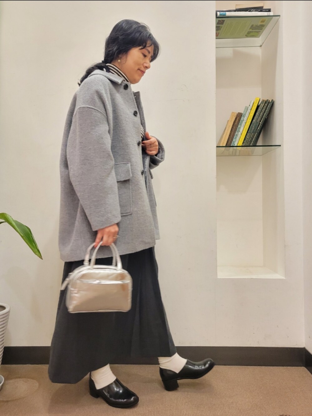 ブラック系のレインシューズ、シルバー系のショルダーバッグ、グレー系のその他アウターを着用したレディースの冬コーディネートの2枚目の写真