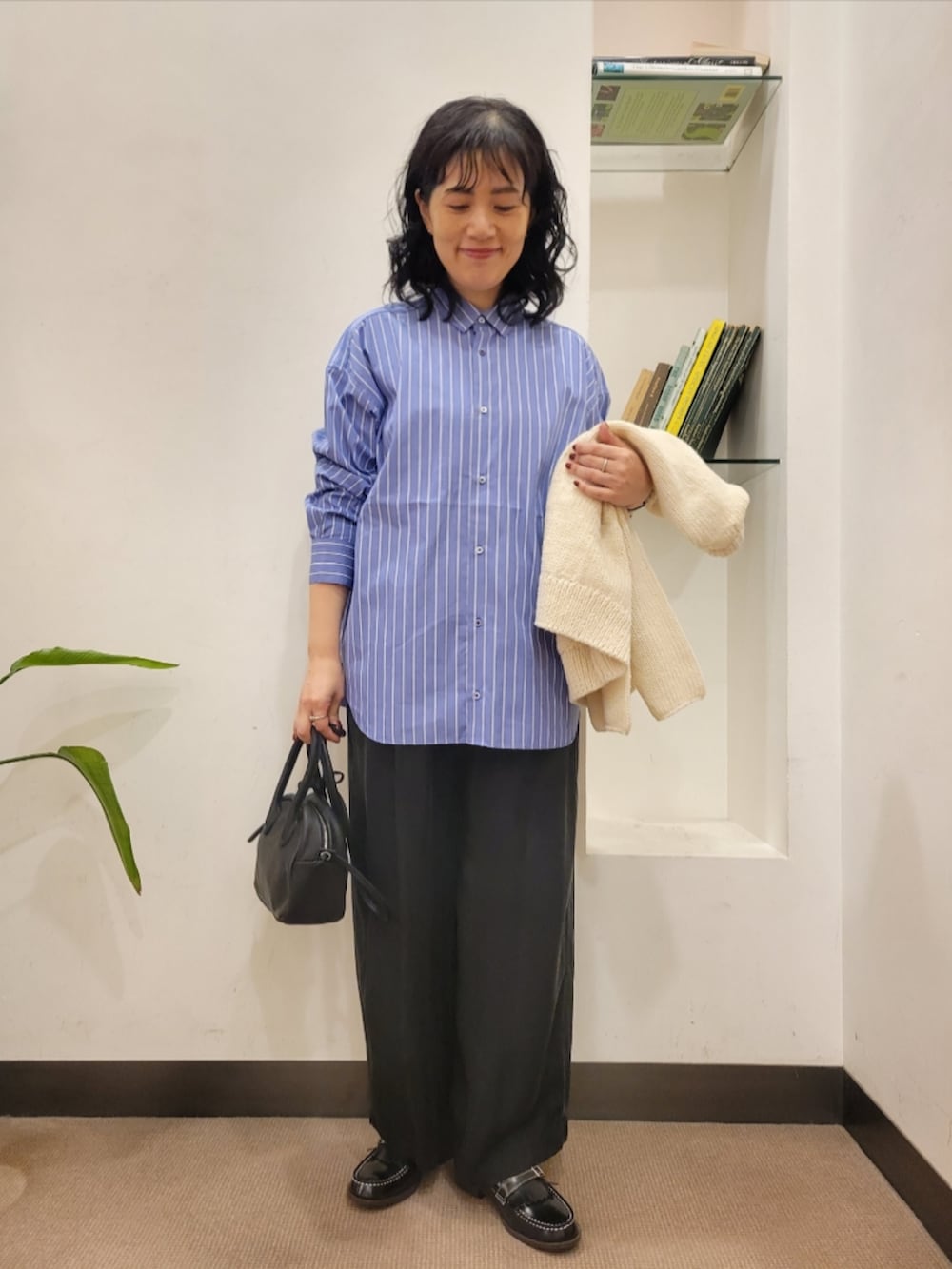 ブラック系のハンドバッグ、ブラック系のローファー、ホワイト系のニット/セーターを着用したレディースの秋コーディネートの4枚目の写真