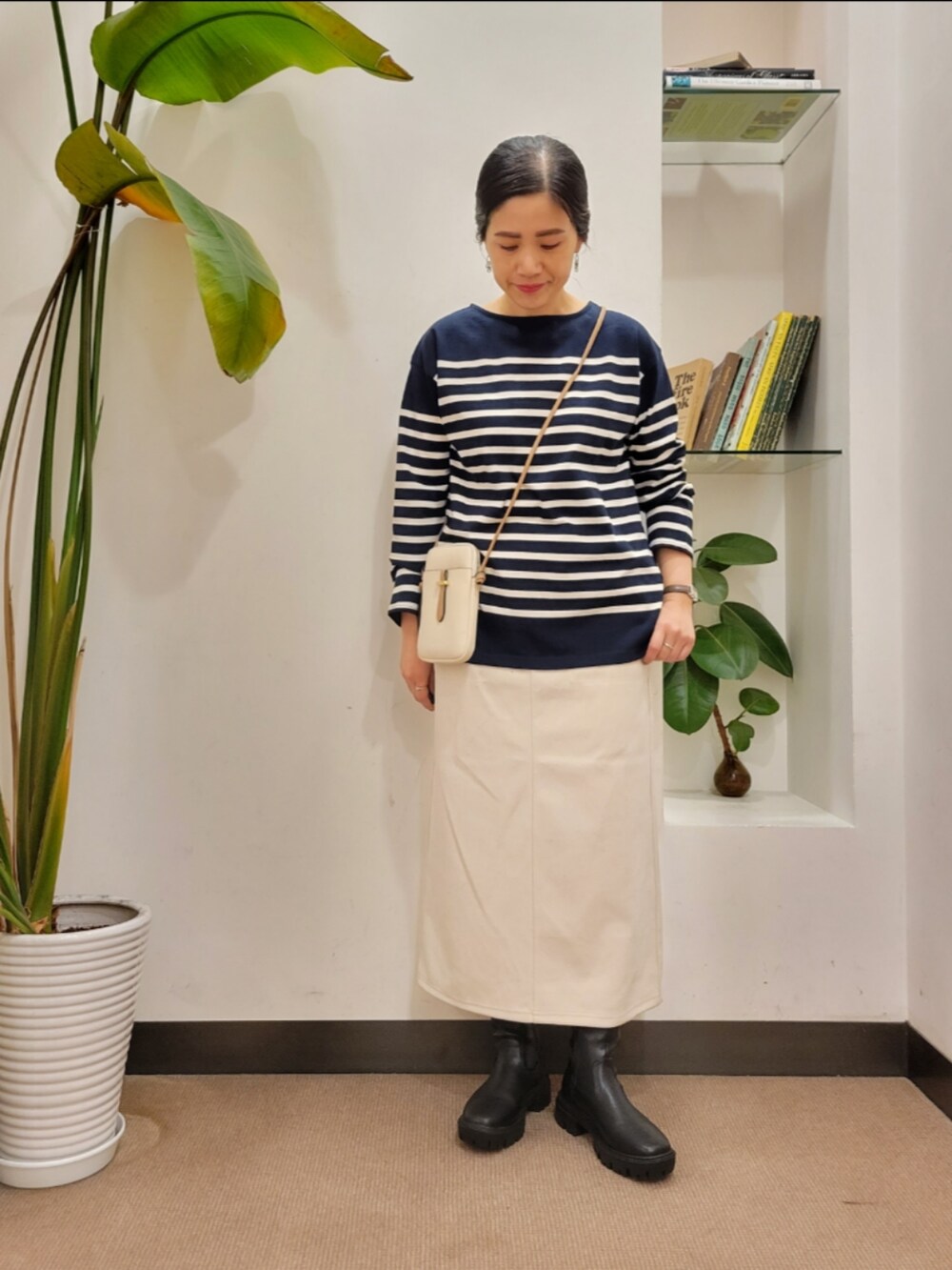 ホワイト系のショルダーバッグ、ブラック系のブーツ、ホワイト系のスカートを着用したレディースの秋コーディネートの2枚目の写真