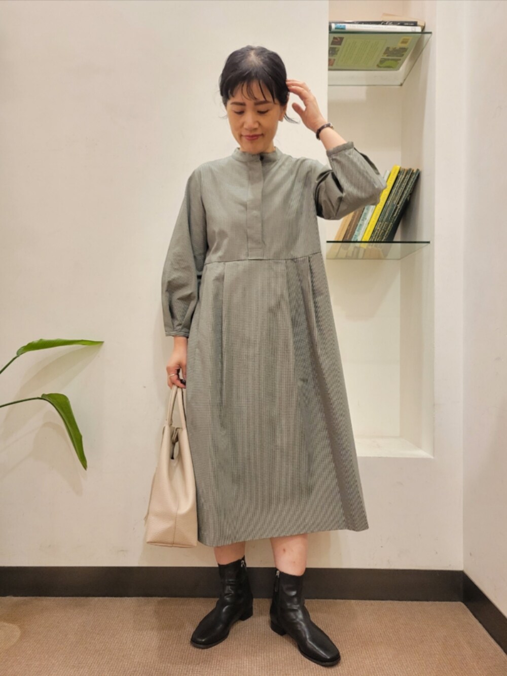 ブラック系のブーツ、グレー系のワンピース、ホワイト系のトートバッグを着用したレディースの秋コーディネートの2枚目の写真