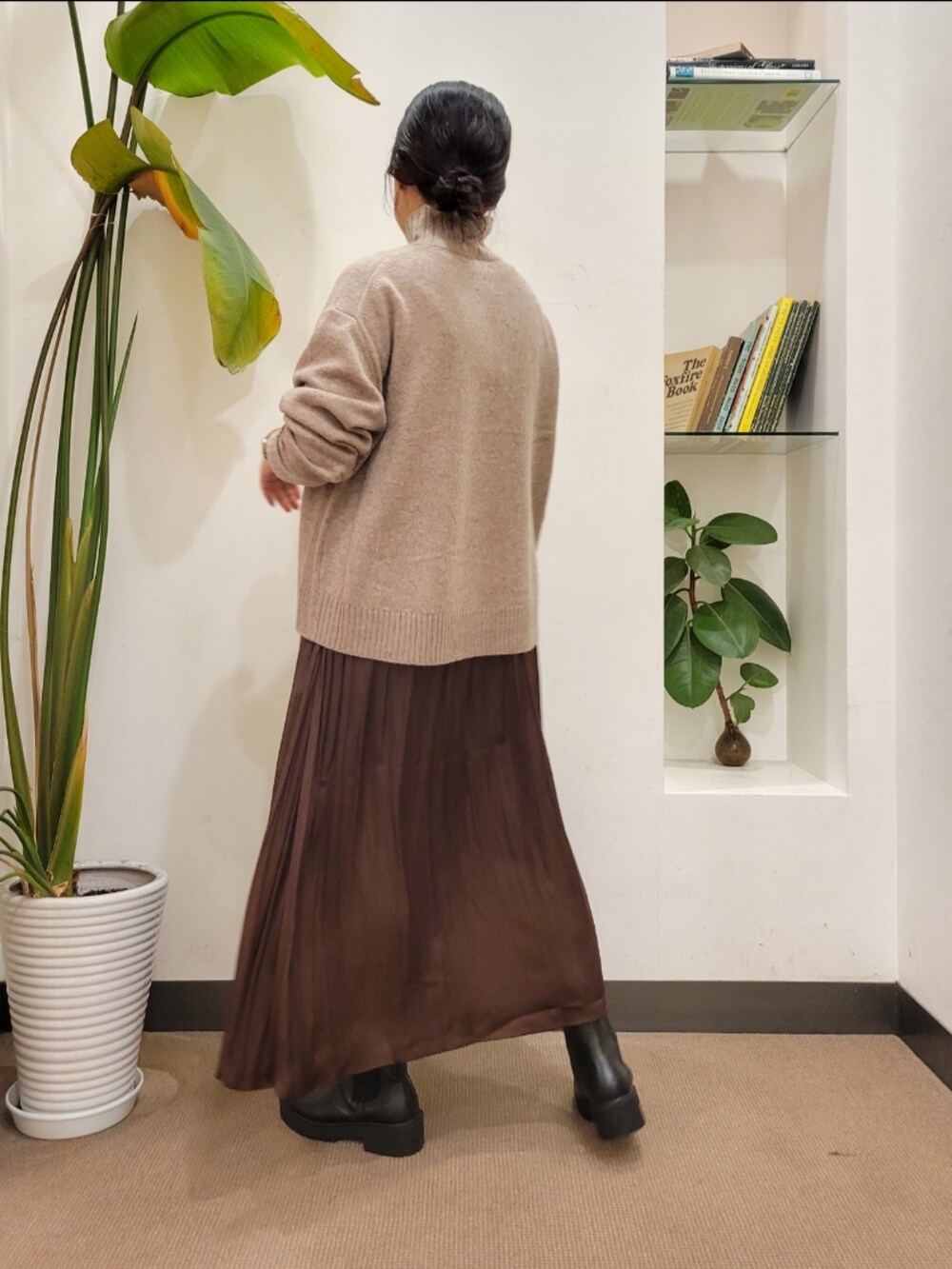 ブラック系のブーツ、ホワイト系のハンドバッグ、ブラウン系のスカートを着用したレディースの秋コーディネートの5枚目の写真