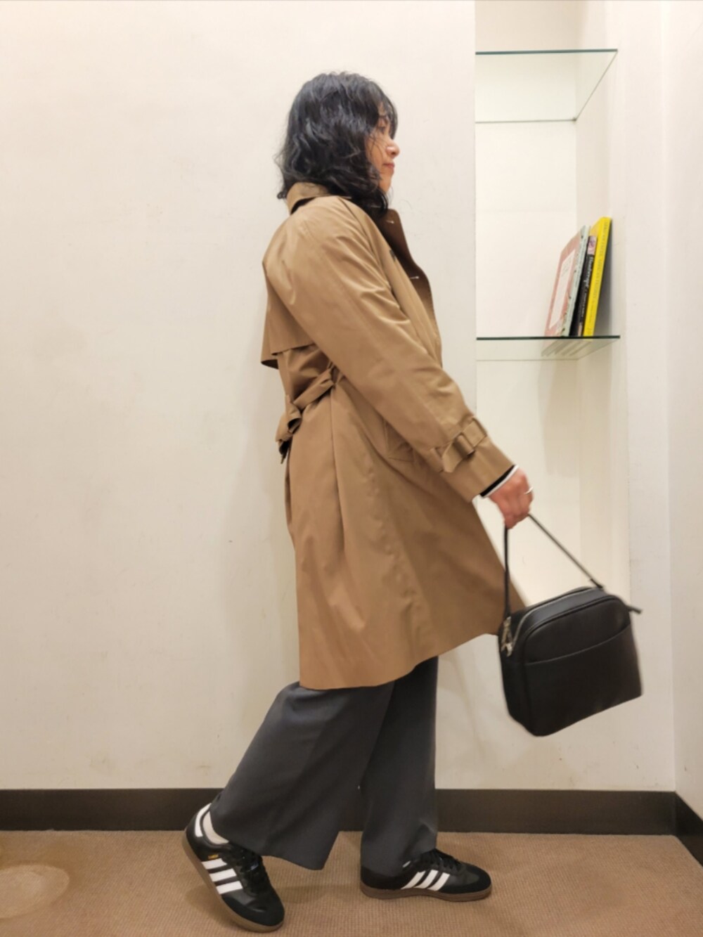 ブラック系のショルダーバッグ、ベージュ系のトレンチコート、グレー系のベストを着用したレディースの冬コーディネートの2枚目の写真