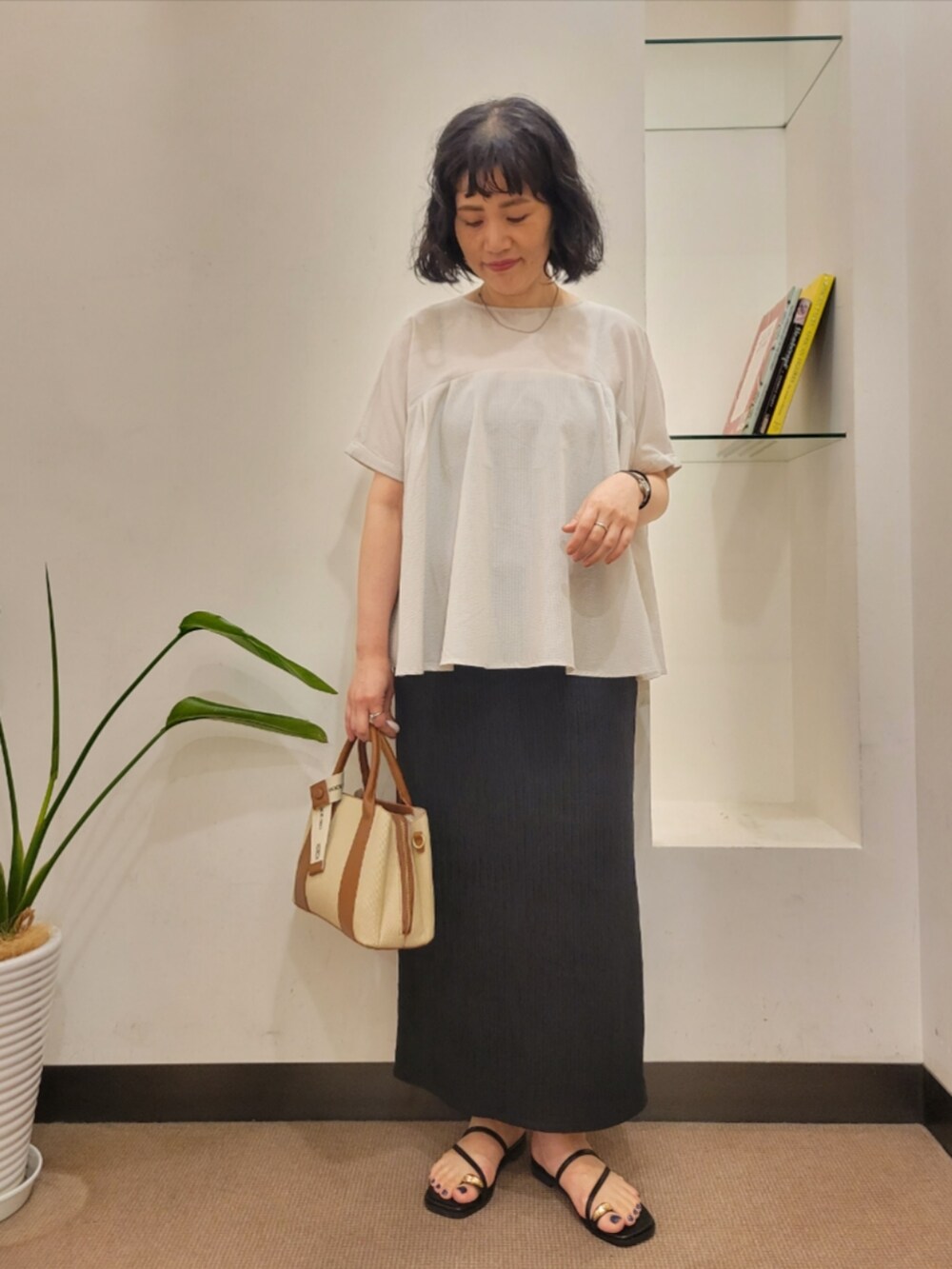 グレー系のシャツ/ブラウス、ブラック系のスカート、ホワイト系のハンドバッグを着用したレディースの夏コーディネートの2枚目の写真