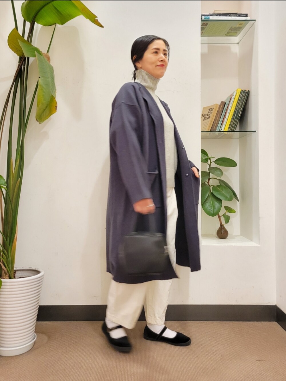 グレー系のノーカラーコート、ホワイト系のその他パンツ、グレー系のニット/セーターを着用したレディースの冬コーディネートの2枚目の写真