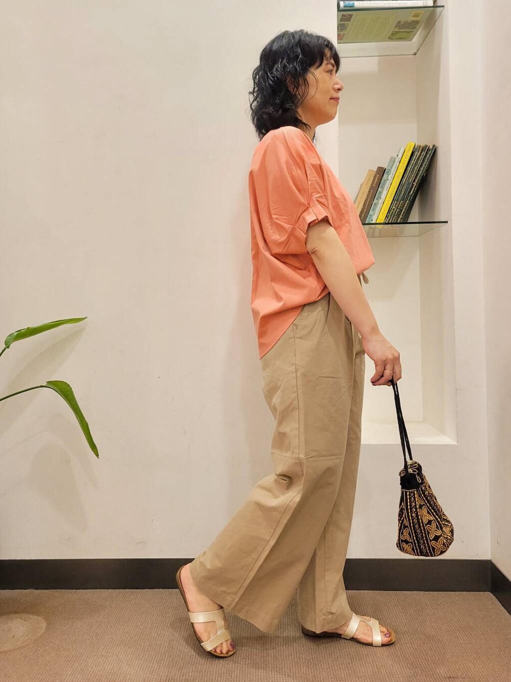 オレンジ系のTシャツ/カットソー、ブラック系のショルダーバッグ、ホワイト系のサンダルを着用したレディースの夏コーディネートの4枚目の写真