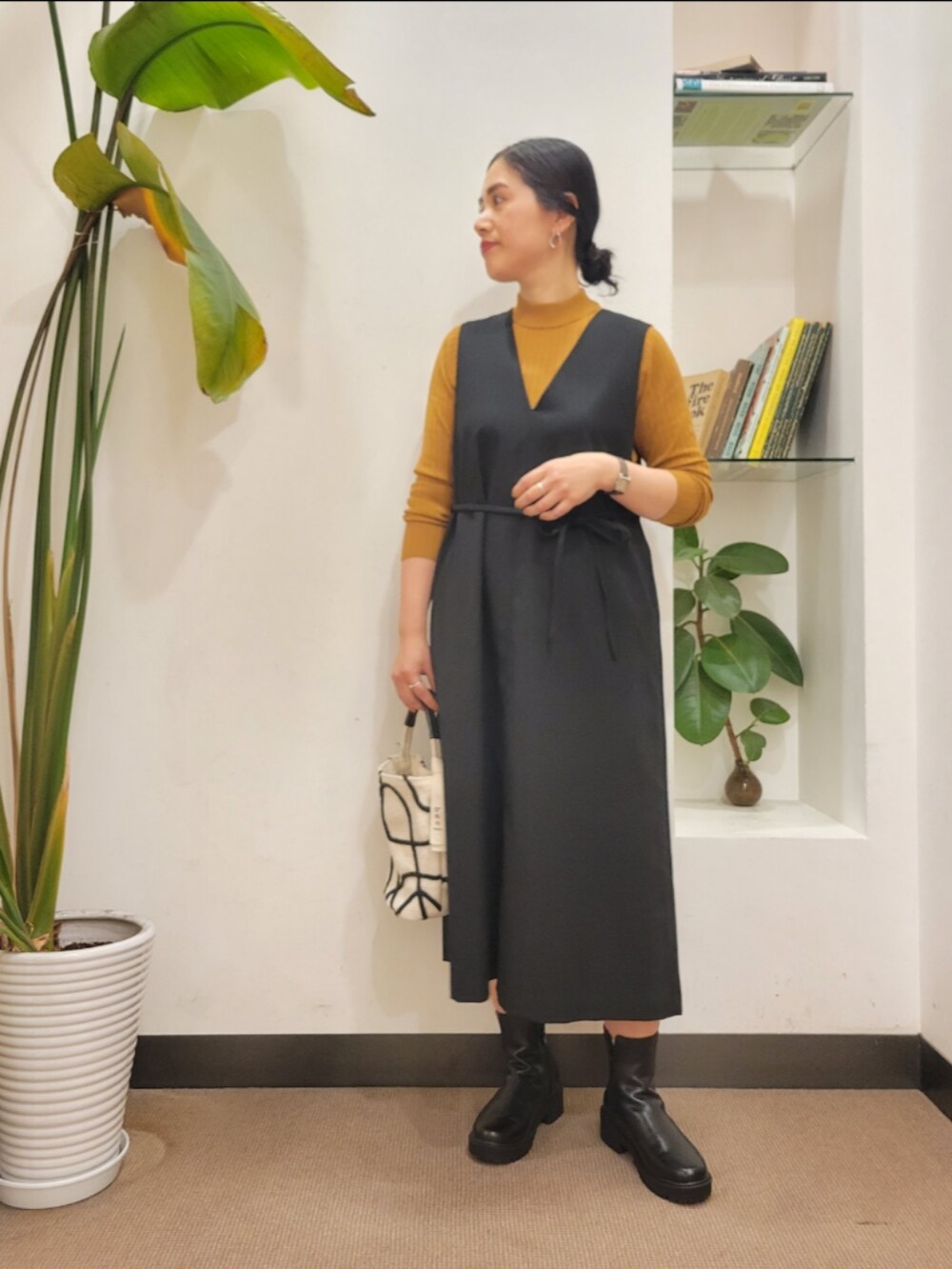 ホワイト系のショルダーバッグ、ブラック系のワンピース、イエロー系のニット/セーターを着用したレディースの秋コーディネートの2枚目の写真