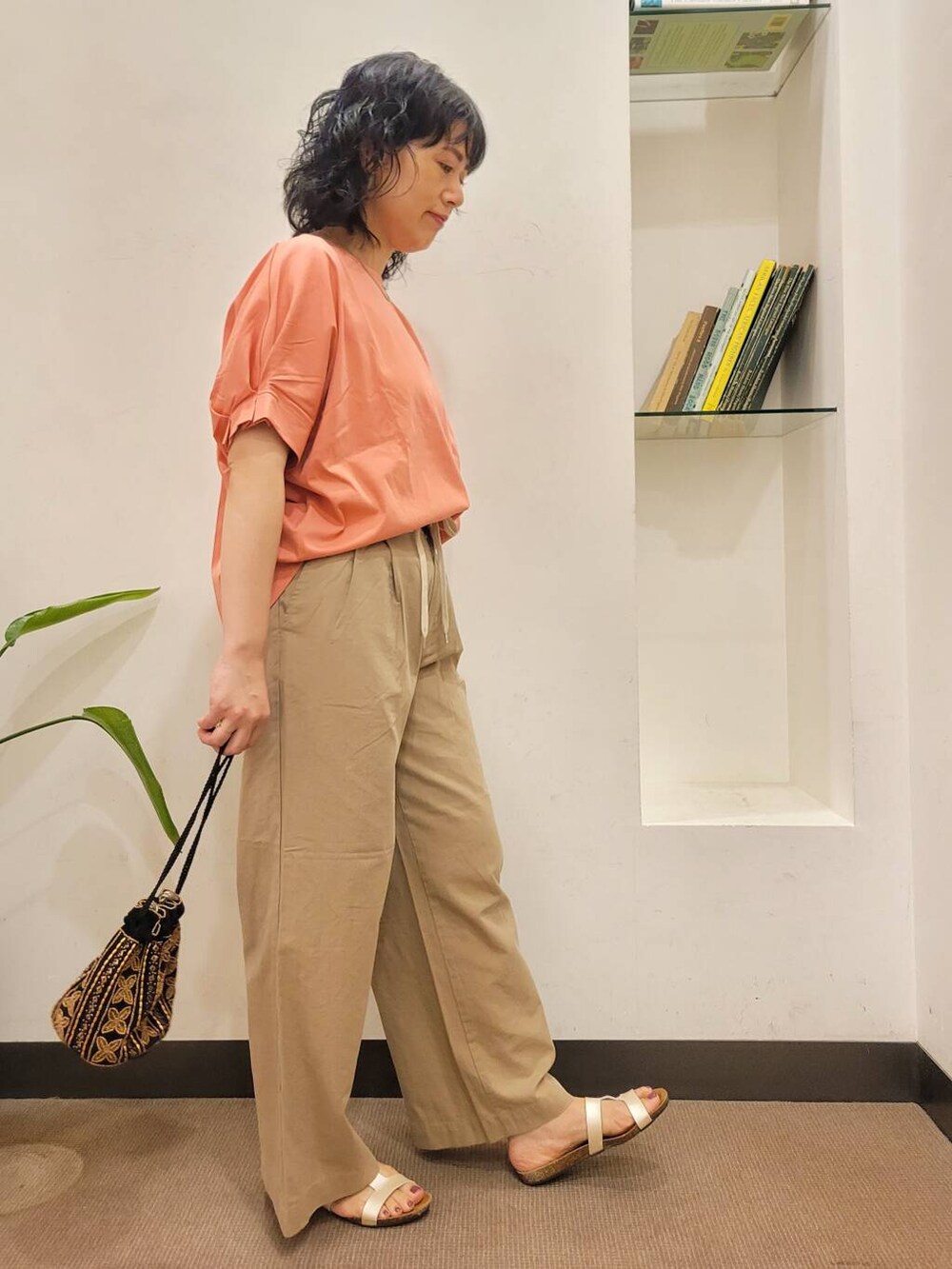 オレンジ系のTシャツ/カットソー、ブラック系のショルダーバッグ、ホワイト系のサンダルを着用したレディースの夏コーディネートの3枚目の写真