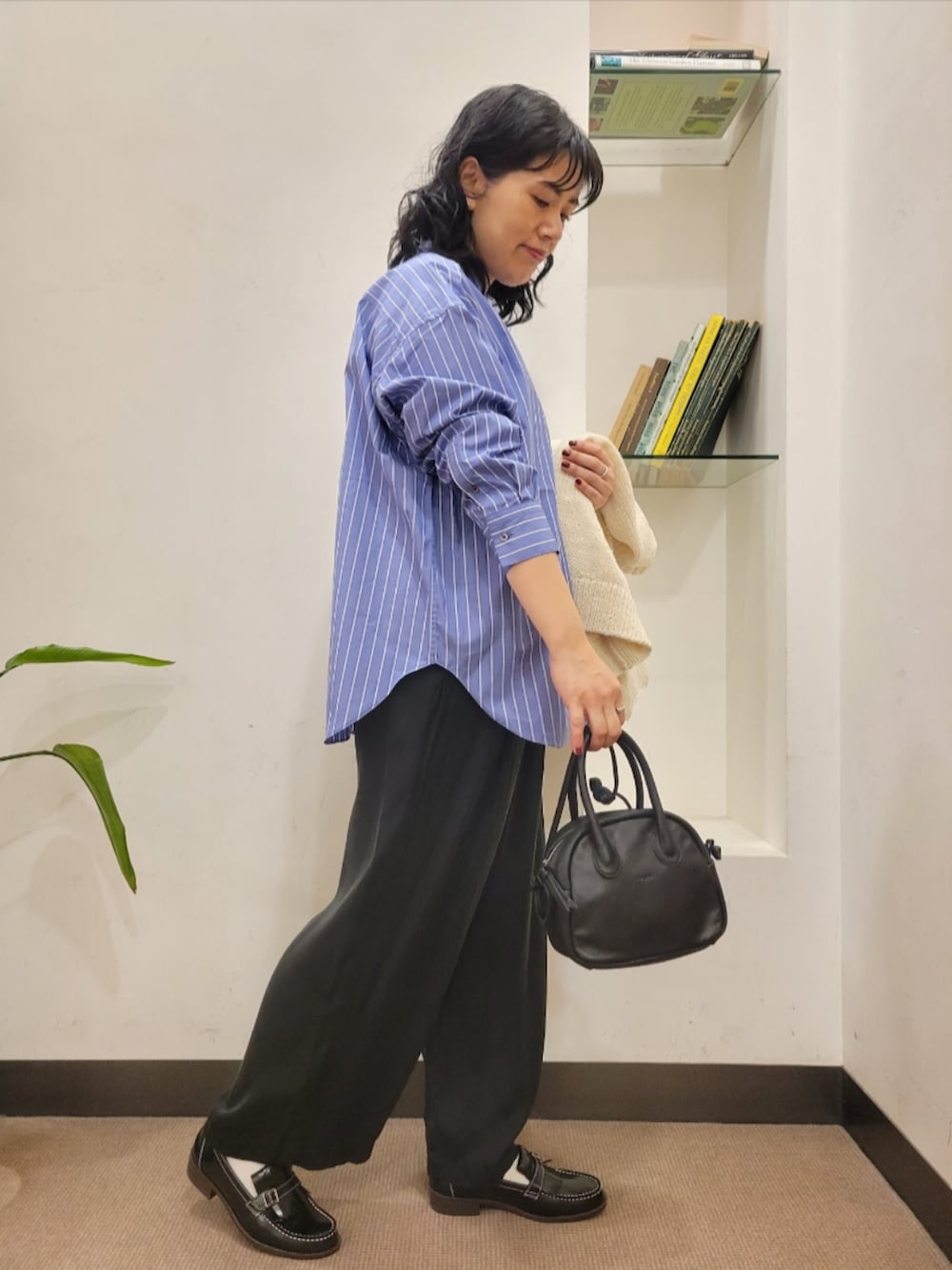 ブラック系のハンドバッグ、ブラック系のローファー、ホワイト系のニット/セーターを着用したレディースの秋コーディネートの5枚目の写真