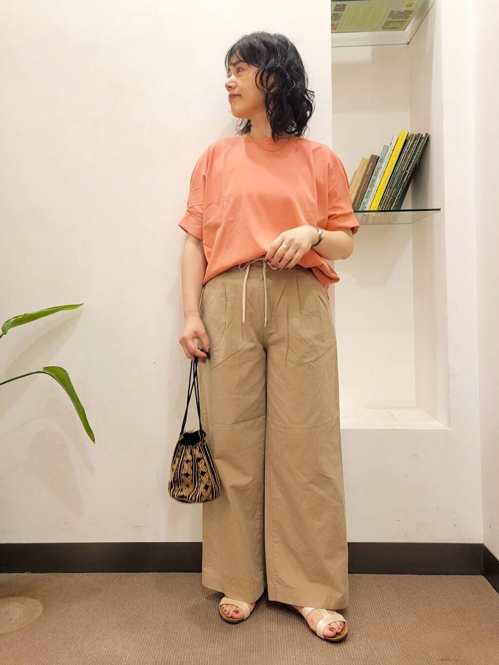 オレンジ系のTシャツ/カットソー、ブラック系のショルダーバッグ、ホワイト系のサンダルを着用したレディースの夏コーディネートの2枚目の写真