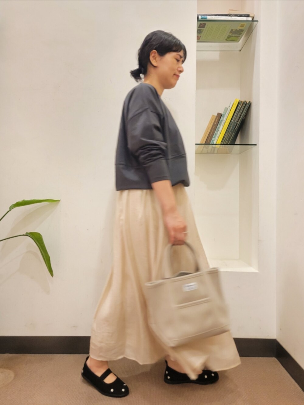 グレー系のTシャツ/カットソー、ベージュ系のスカート、ブラック系のスニーカーを着用したレディースの秋コーディネートの3枚目の写真