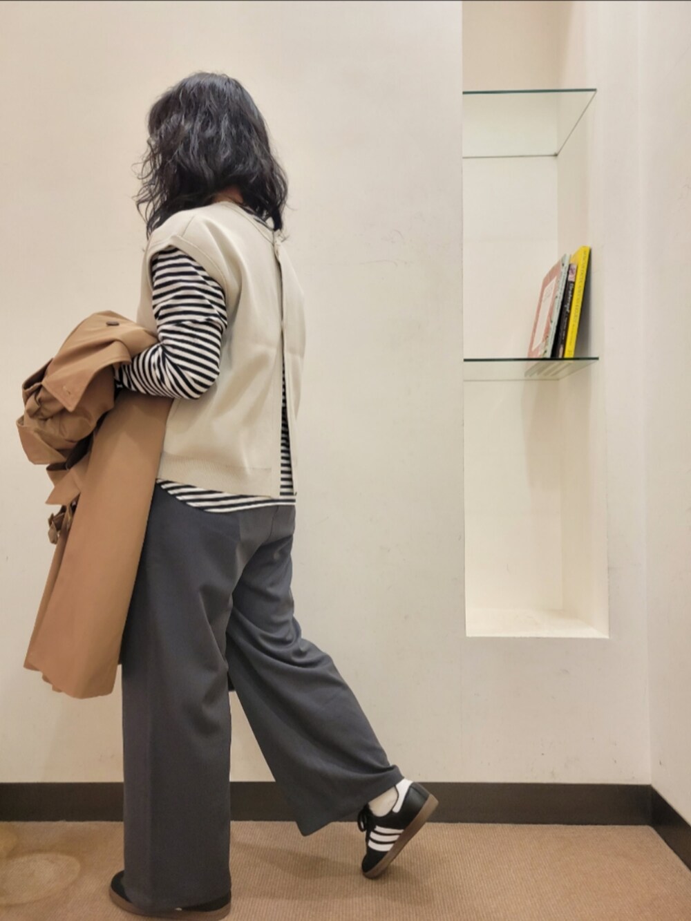 ブラック系のショルダーバッグ、ベージュ系のトレンチコート、グレー系のベストを着用したレディースの冬コーディネートの5枚目の写真