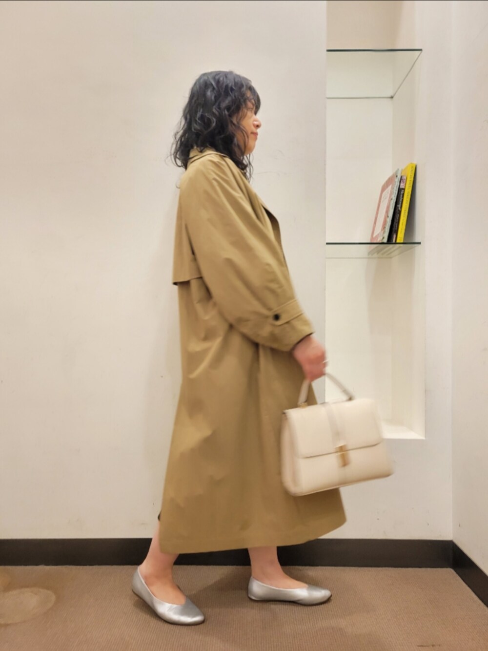 ベージュ系のトレンチコート、ブラック系のワンピース、シルバー系のパンプスを着用したレディースの冬コーディネートの2枚目の写真