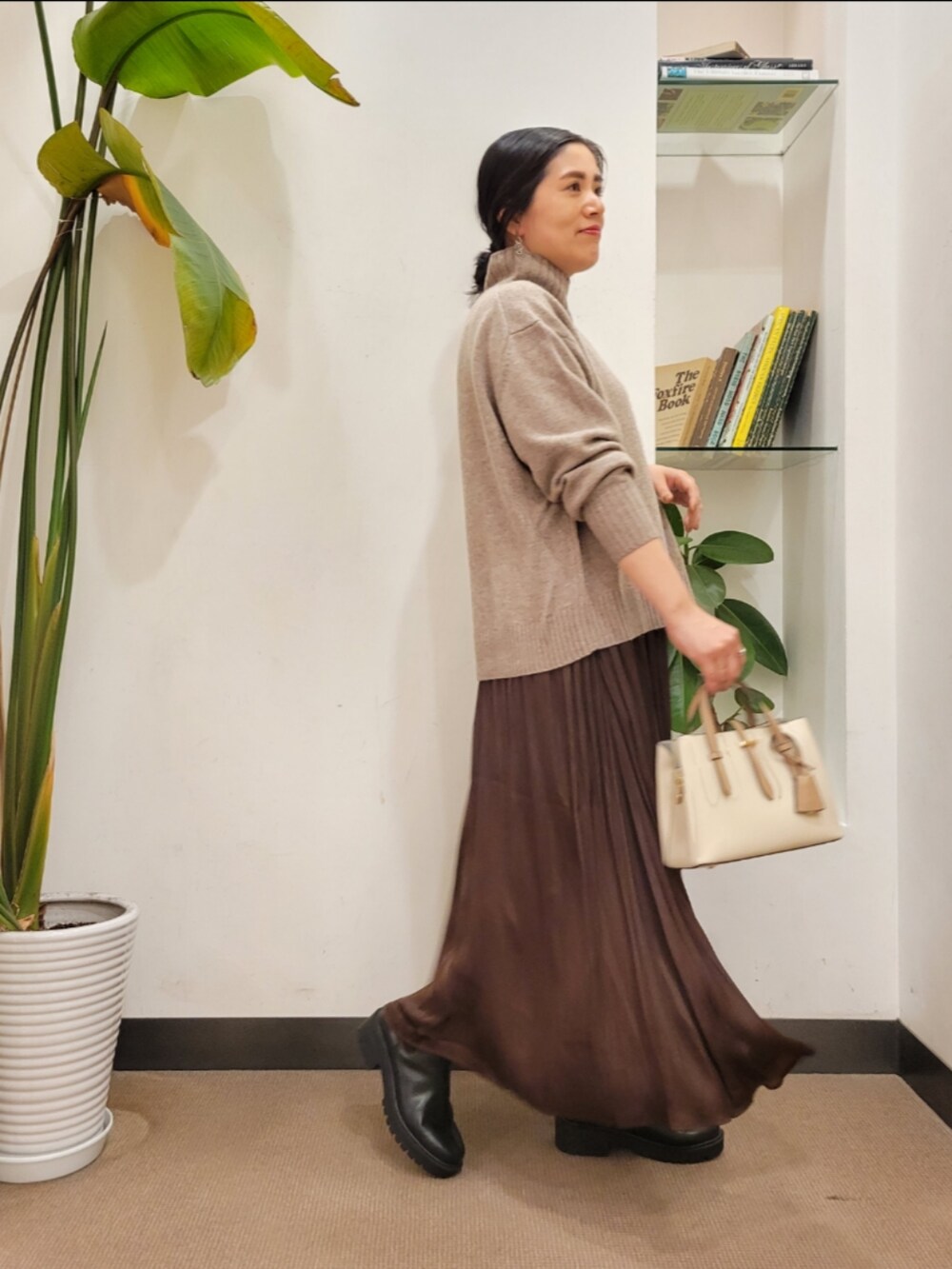 ブラック系のブーツ、ホワイト系のハンドバッグ、ブラウン系のスカートを着用したレディースの秋コーディネートの4枚目の写真