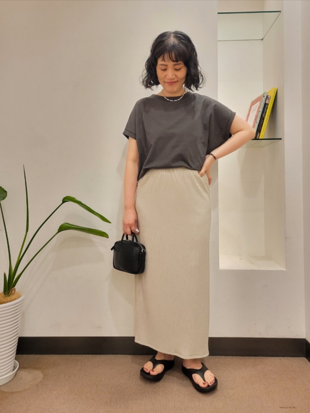 ブラック系のショルダーバッグ、グレー系のTシャツ/カットソー、ベージュ系のスカートを着用したレディースの夏コーディネートの3枚目の写真