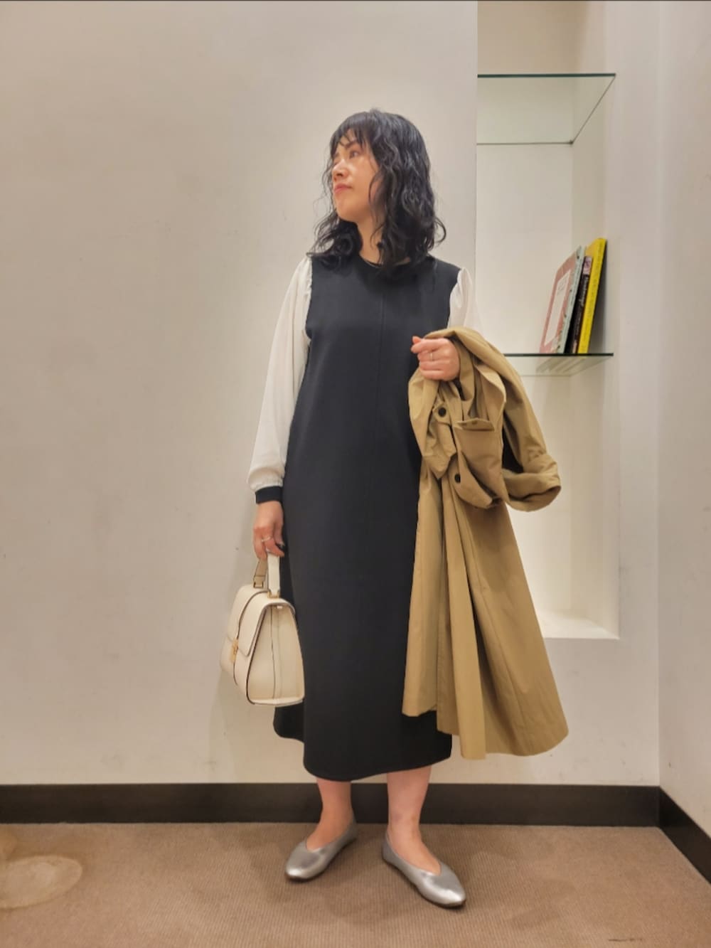 ベージュ系のトレンチコート、ブラック系のワンピース、シルバー系のパンプスを着用したレディースの冬コーディネートの4枚目の写真