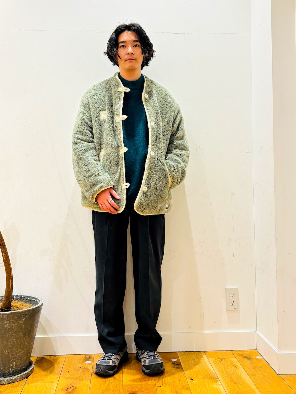 グリーン系のニット/セーター、ブラック系のその他パンツ、ホワイト系のその他アウターを着用したメンズの冬コーディネートの2枚目の写真