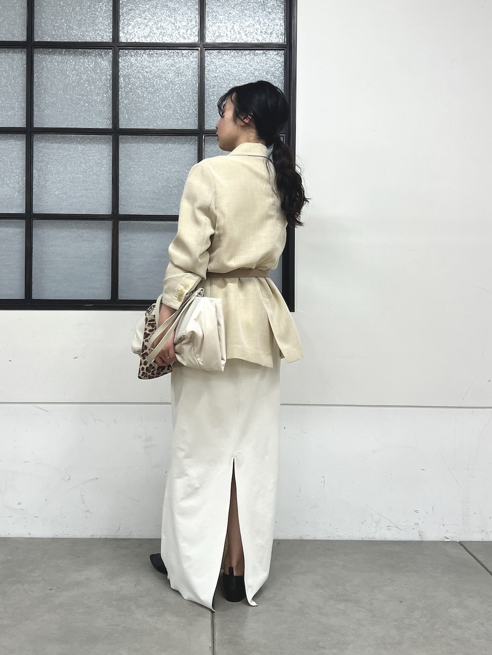 ブラック系のスリッポン、ホワイト系のスカート、ベージュ系のテーラードジャケットを着用したレディースの春コーディネートの3枚目の写真