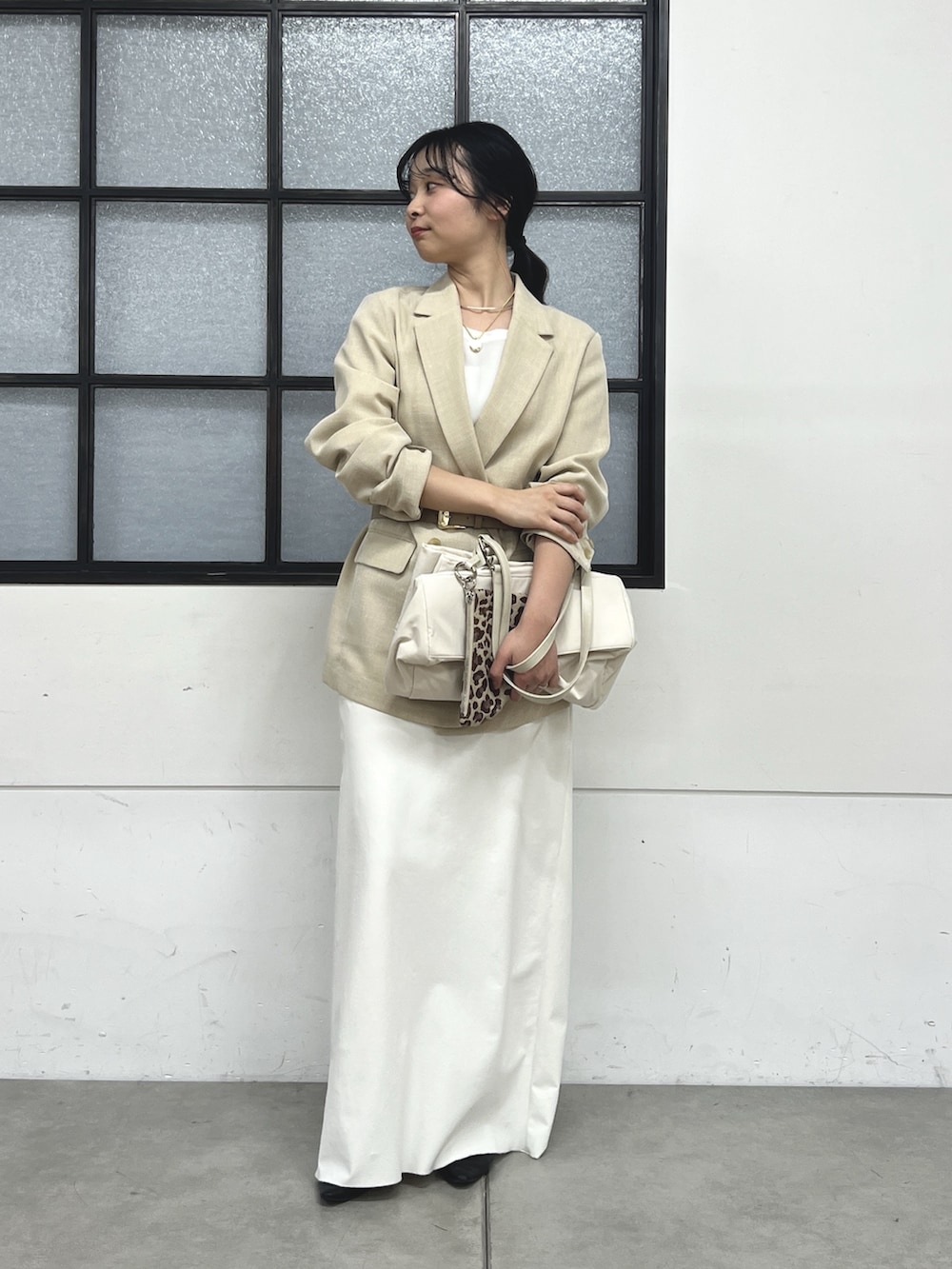 ブラック系のスリッポン、ホワイト系のスカート、ベージュ系のテーラードジャケットを着用したレディースの春コーディネートの2枚目の写真