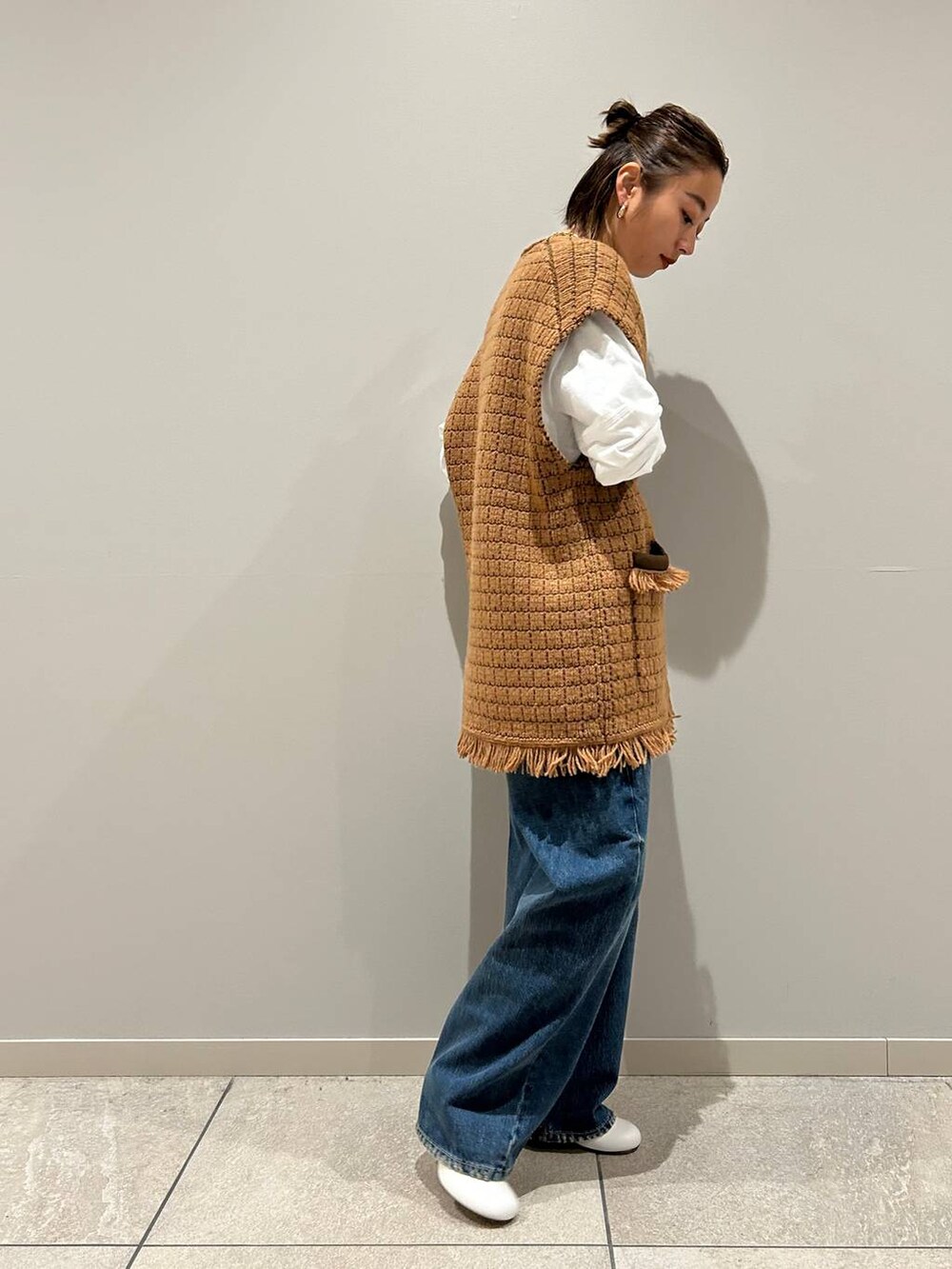 ブルー系のデニムパンツ、ホワイト系のTシャツ/カットソー、イエロー系のベストを着用したレディースの秋コーディネートの3枚目の写真