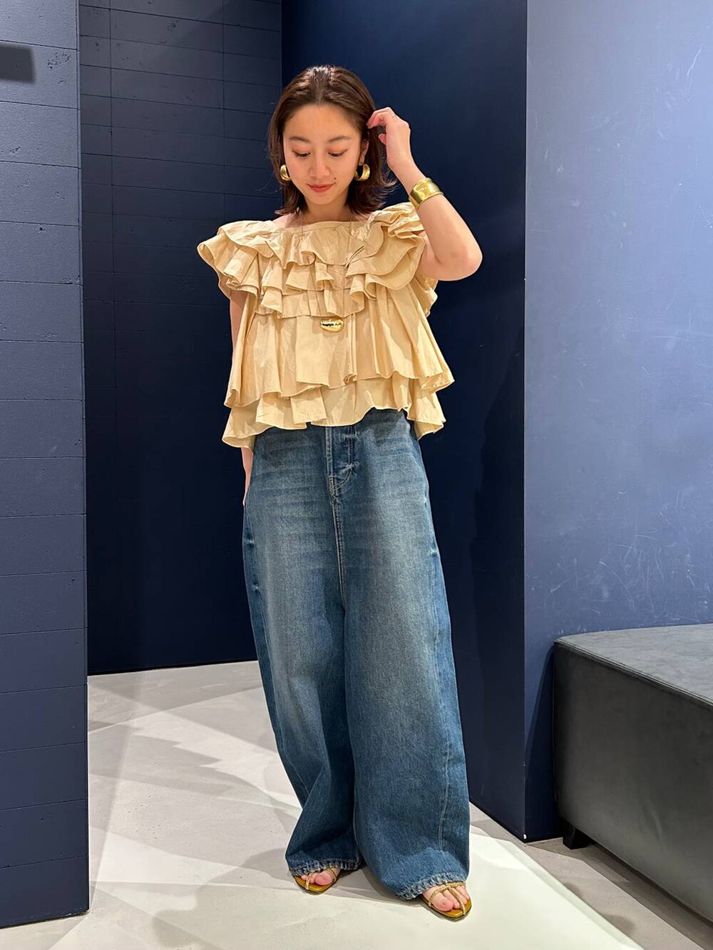 ブルー系のデニムパンツ、ベージュ系のシャツ/ブラウス、ゴールド系のバングル/リストバンドを着用したレディースの春コーディネートの2枚目の写真