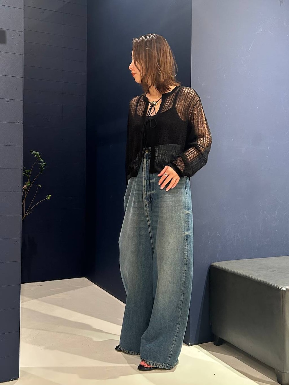 ブルー系のデニムパンツ、ブラック系のニット/セーター、ゴールド系のネックレスを着用したレディースの夏コーディネートの3枚目の写真