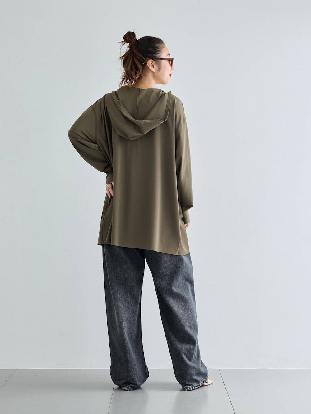 ブラック系のデニムパンツ、グリーン系のラッシュガードを着用したレディースの夏コーディネートの2枚目の写真