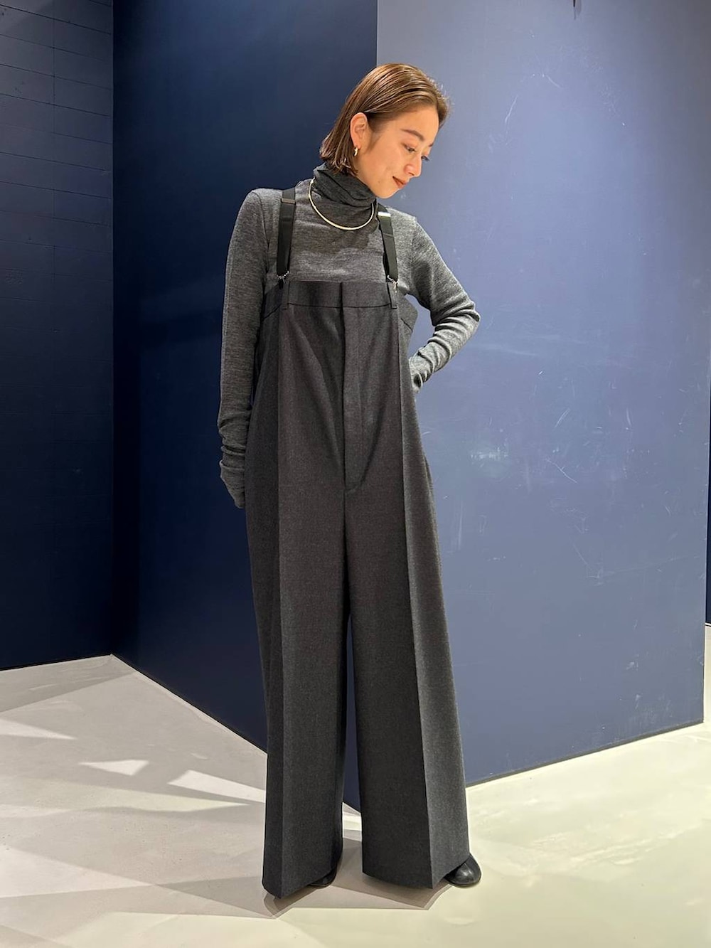 グレー系のサロペット/オーバーオール、グレー系のニット/セーター、ゴールド系のチョーカーを着用したレディースの冬コーディネートの2枚目の写真