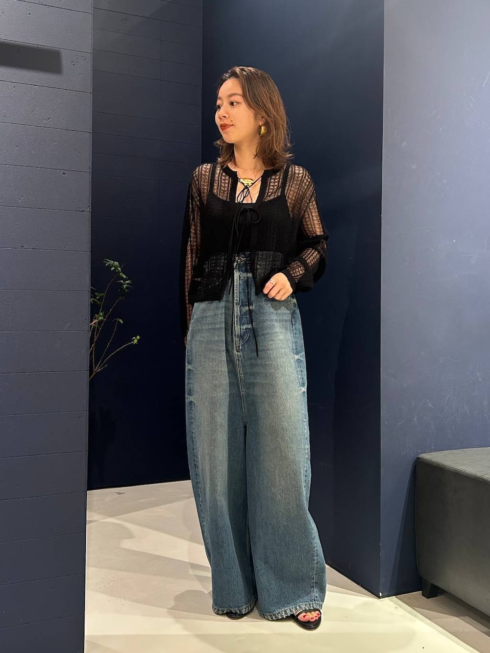 ブルー系のデニムパンツ、ブラック系のニット/セーター、ゴールド系のネックレスを着用したレディースの夏コーディネートの2枚目の写真